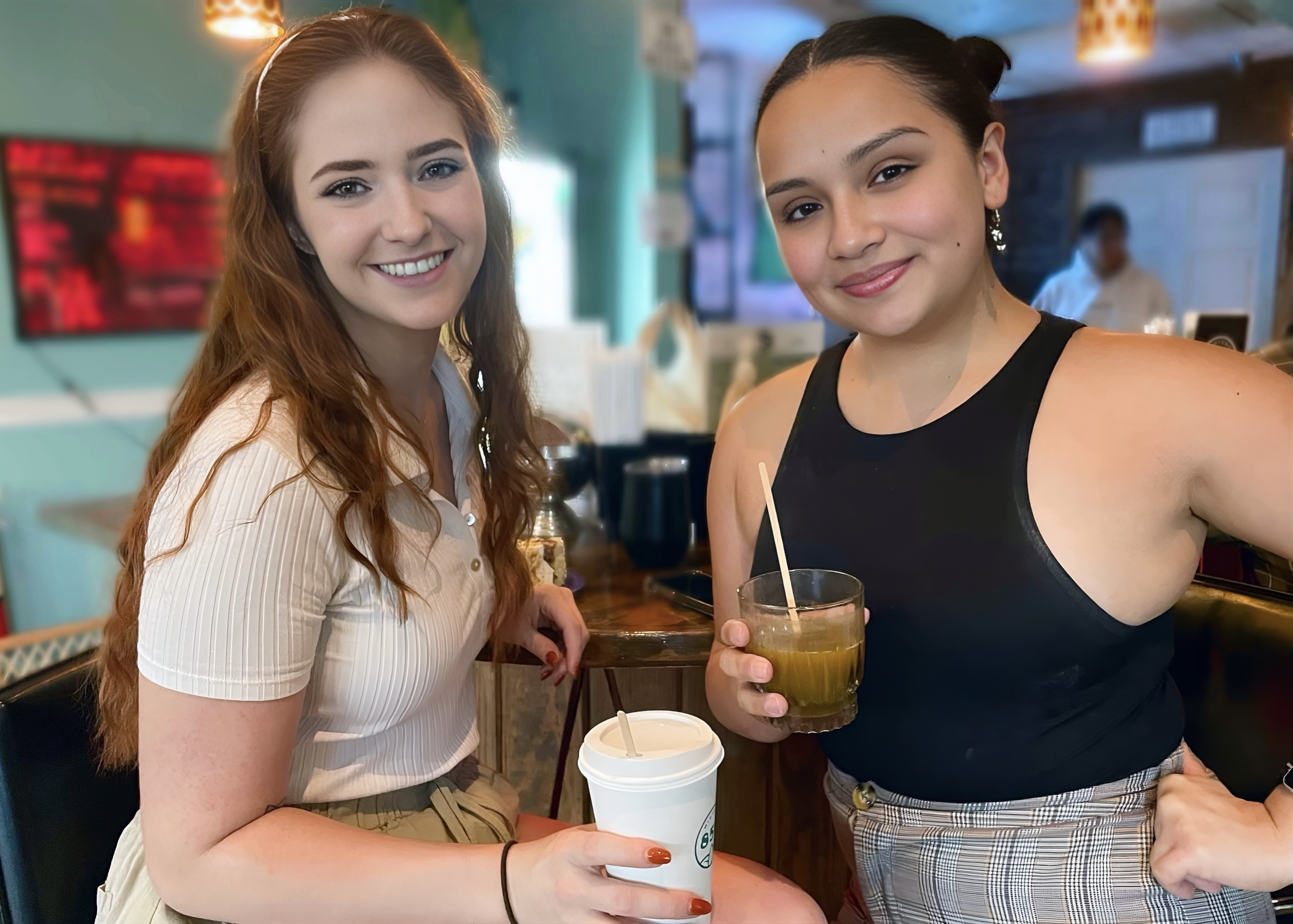 Lauren and Tiffany, both kava regulars, holding their drinks and smiling at Midtown Kava Lounge’s bar